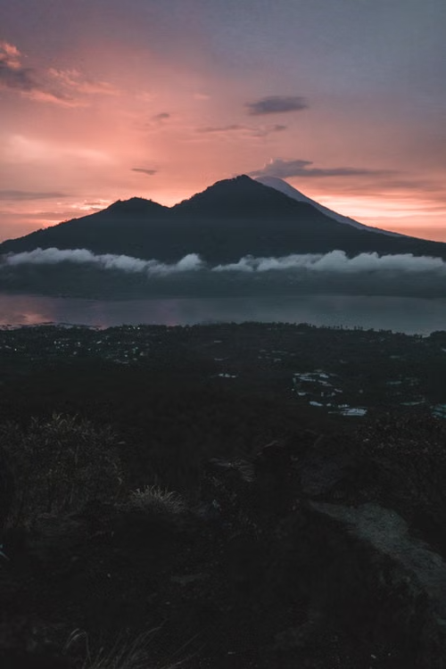 Mount Batur volcano silhouette at sunrise with pink sky