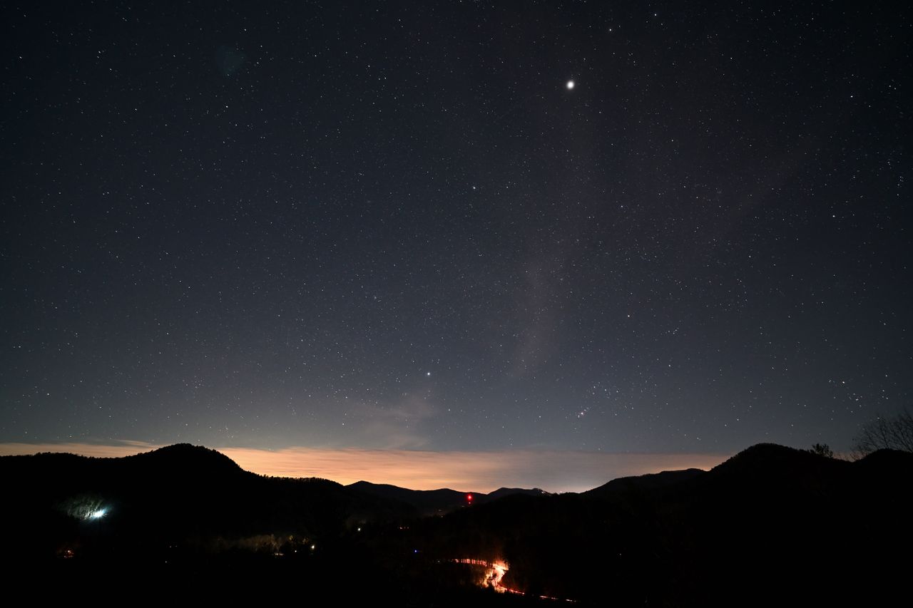 Starry night sky over mountains before dawn